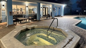 Een overdekt buitengebied met een zwembad, zitplaatsen en een spa.