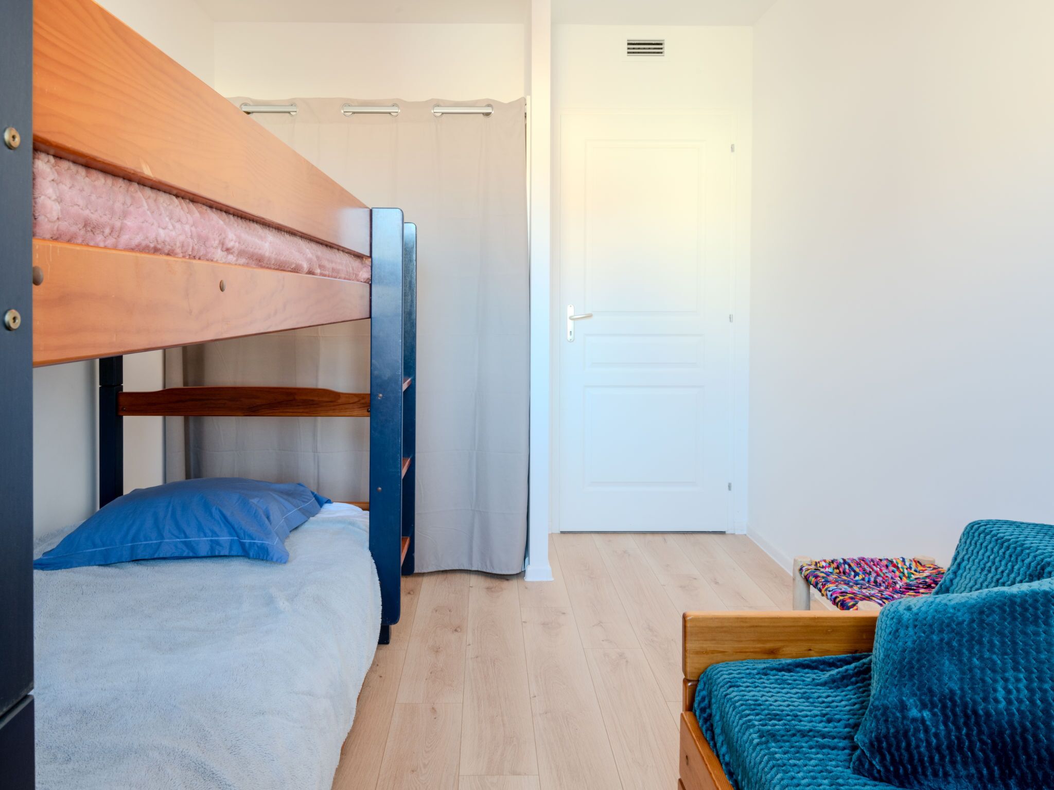 Una camera del dormitorio con letti a castello, una porta e un tavolino con una coperta colorata.