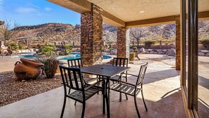 Une terrasse extérieure avec des piliers en pierre, une piscine et des chaises longues.