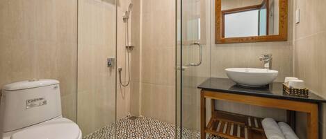 A bathroom with a glass-enclosed shower, a white toilet, a sink with a mirror above it, and a shelf with towels.