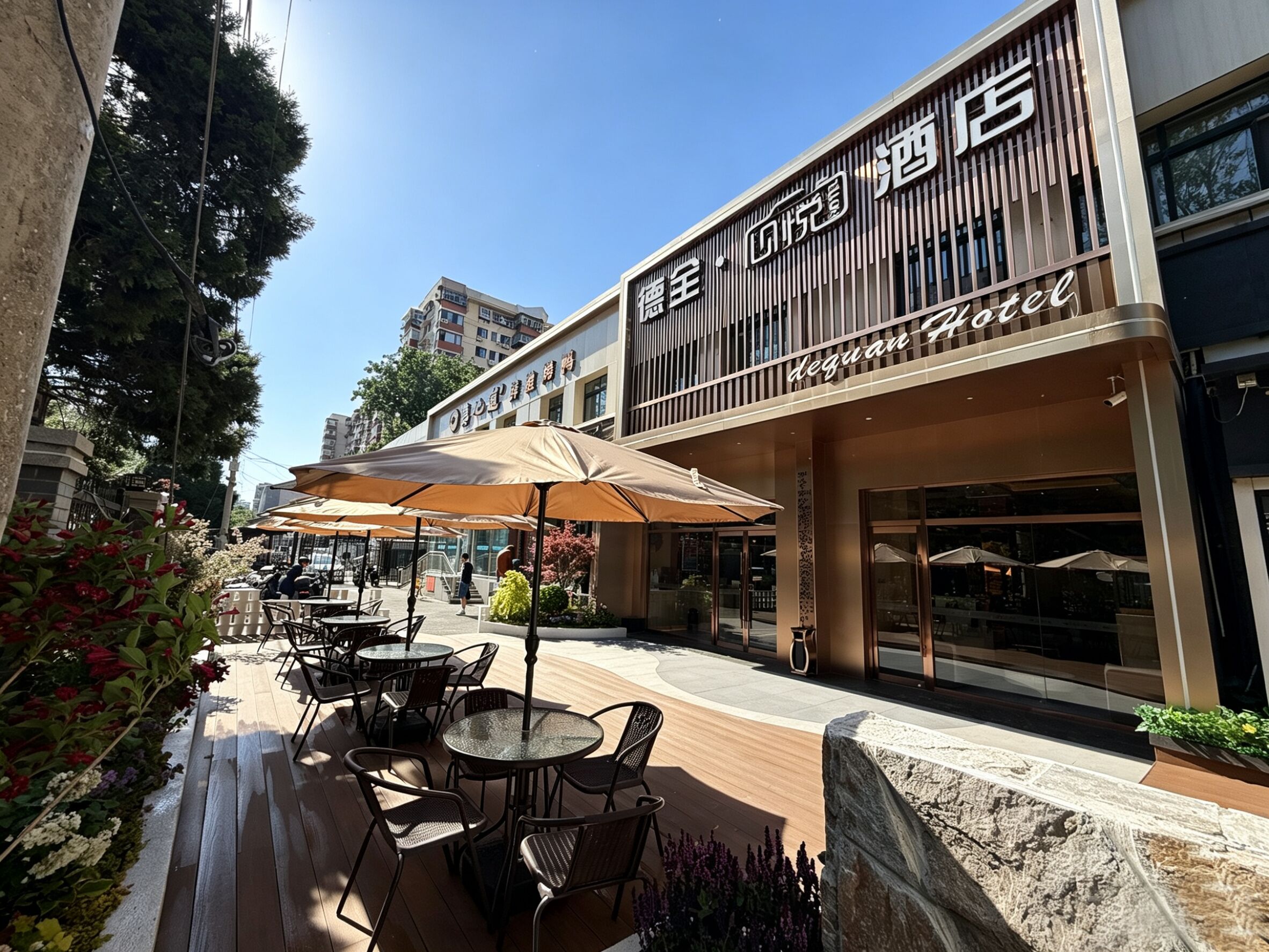 L’extérieur d’un hôtel avec des places assises en plein air, un ciel dégagé et une façade moderne.