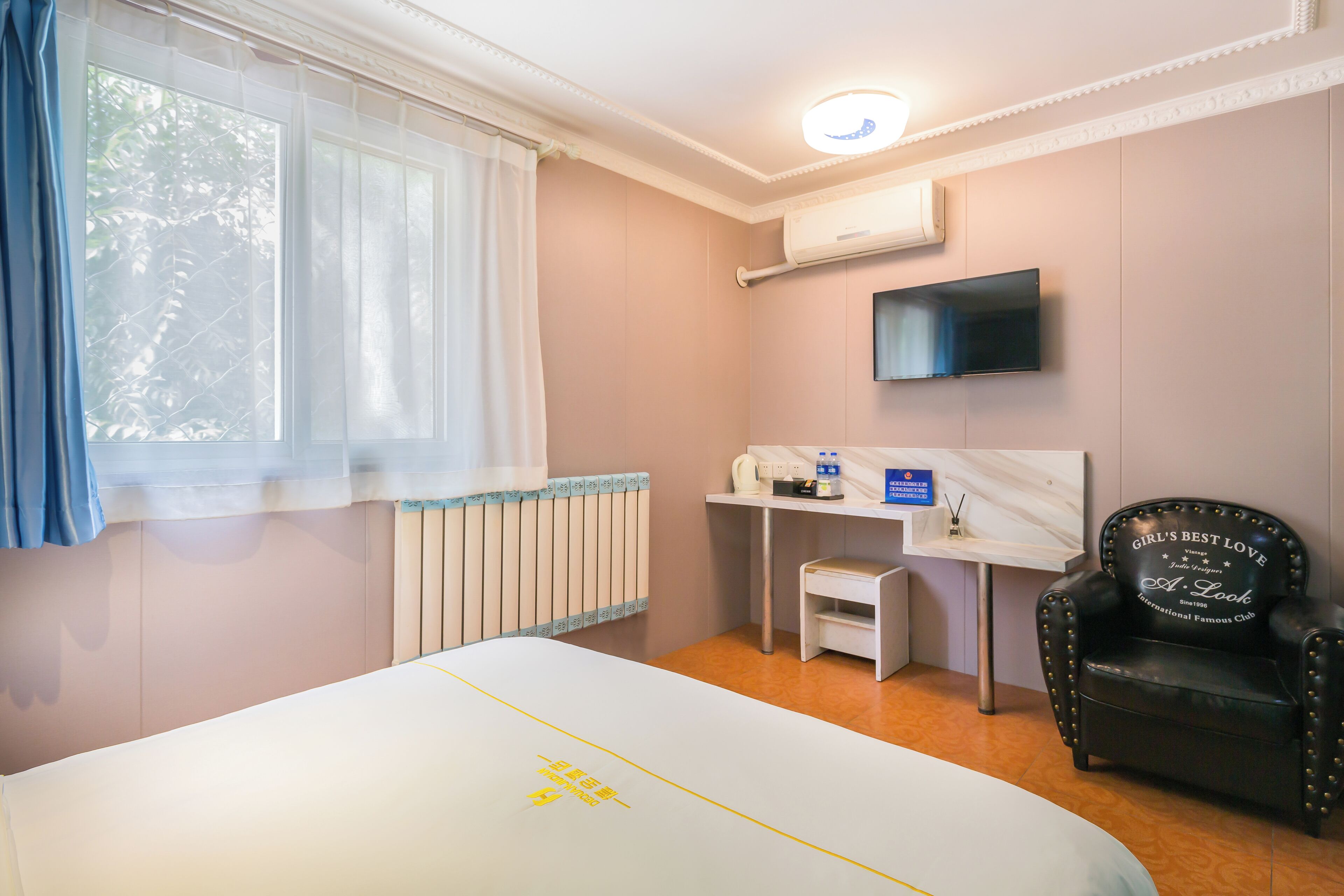 Una habitación de hotel con cama, escritorio, silla, televisor y ventana con cortinas.