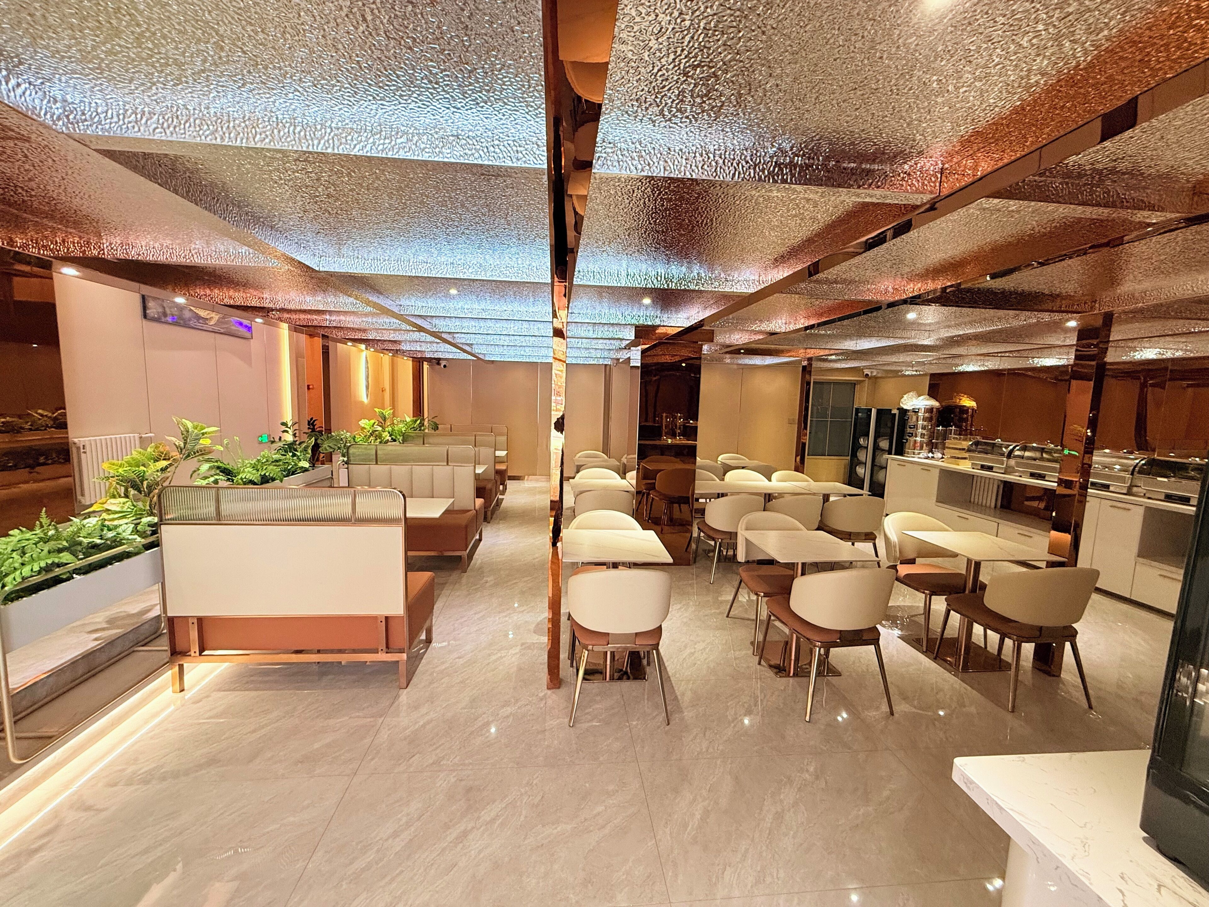 A modern restaurant with booth seating and individual tables, featuring a polished marble floor and a textured ceiling.
