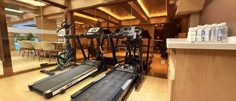 A gym with treadmills, exercise bikes, and a water station.