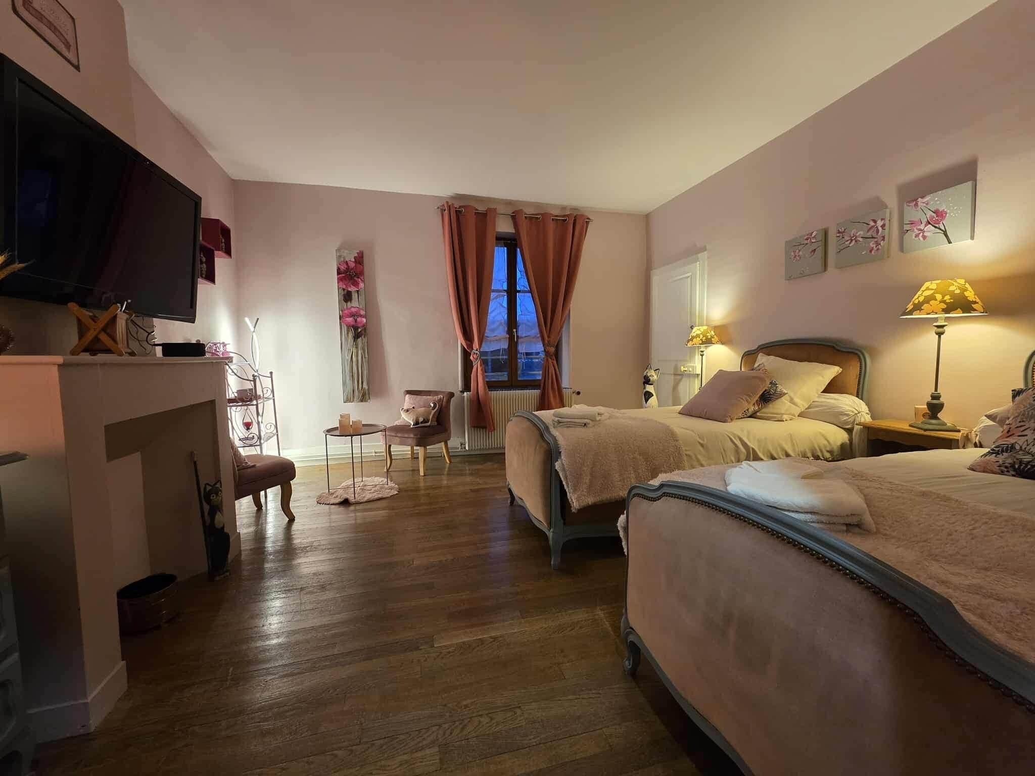 A bedroom with two beds, a TV, a desk, and a chair.
