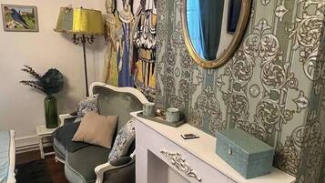 Una habitación con un sofá gris, una consola blanca con espejo y un papel tapiz estampado.