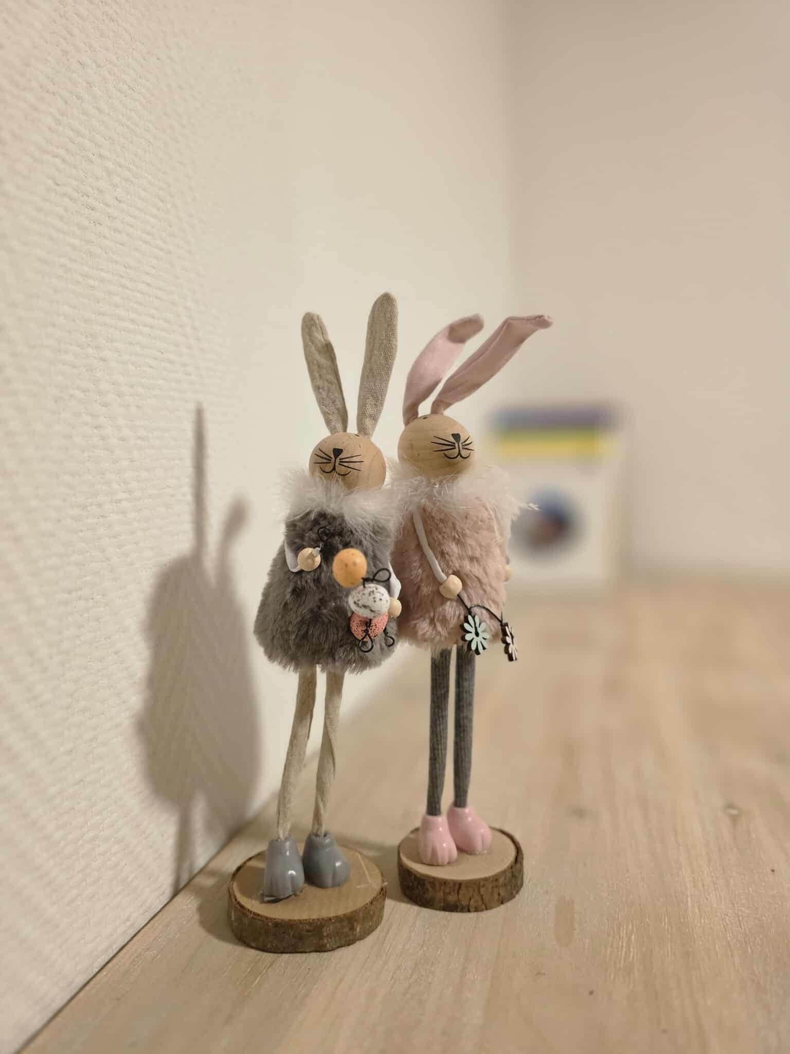 Two small figurines of rabbits on wooden bases.