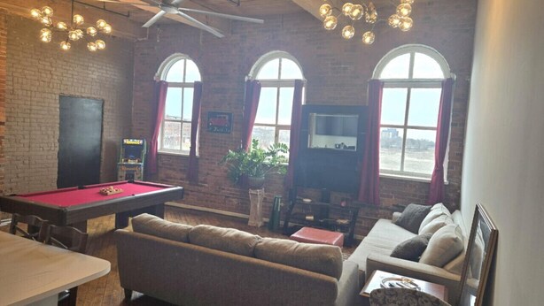 A cozy room with a pool table, a sofa, a television, and a ceiling fan. - Detroit Riverview Loft (Detroit)