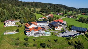 An aerial view of a residential area with multiple houses, a parking area, and a solar panel installation. - Marianne by Interhome (Sankt Englmar)