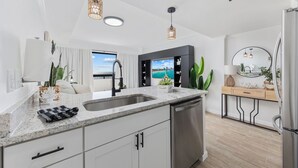 A modern kitchen with a large island, stainless steel appliances, and pendant lighting. - #2 Dreamscapes Oceanfront Oasis, Sea Pointe 605 (North Myrtle Beach)