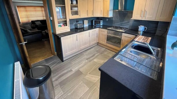 Una cocina moderna con armarios de madera clara, una encimera negra y un horno empotrado.