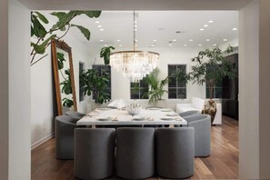 A modern dining area with a chandelier, round table, and grey upholstered chairs. - Luxury 4BD Gold Coast Penthouse with Deck & Views (Chicago)