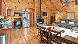 A wooden cabin interior with a kitchen, dining area, and living room. - "Ultimate Luxe Escape with Private Movie Theater and Game Room" (Nelsonville)