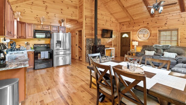 A wooden cabin interior with a kitchen, dining area, and living room. - "Ultimate Luxe Escape with Private Movie Theater and Game Room" (Nelsonville)