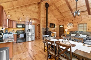 A wooden cabin interior with a kitchen, dining area, and living room. - "Ultimate Luxe Escape with Private Movie Theater and Game Room" (Nelsonville)