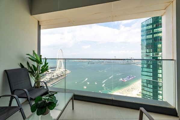 Un balcón con vistas a una ciudad costera, incluyendo un puente y un edificio alto.