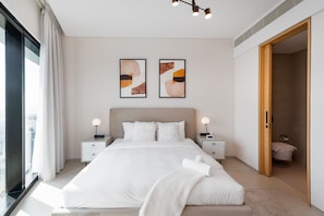 Un dormitorio moderno con una cama grande, dos mesitas de noche con lámparas y una obra de arte en la pared.