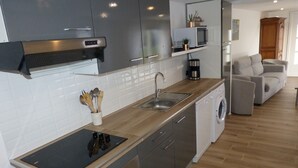 Una cocina moderna con armarios grises, una placa de inducción negra, un lavavajillas integrado y una encimera de madera.
