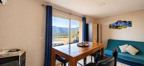 Une pièce avec une table en bois, des chaises, un canapé et une vue sur les montagnes par une grande fenêtre.