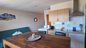 Una cocina compacta con una mesa de madera, un lavamanos y un refrigerador negro.