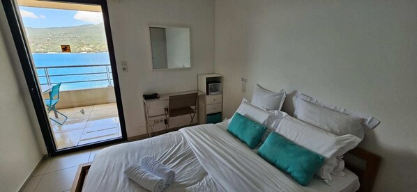 A hotel room with a bed, a desk, a chair, and a view of the sea. - One-Bedroom Apartment on the Beachfront A603, Right on the Water & Centrally Located (Propriano)