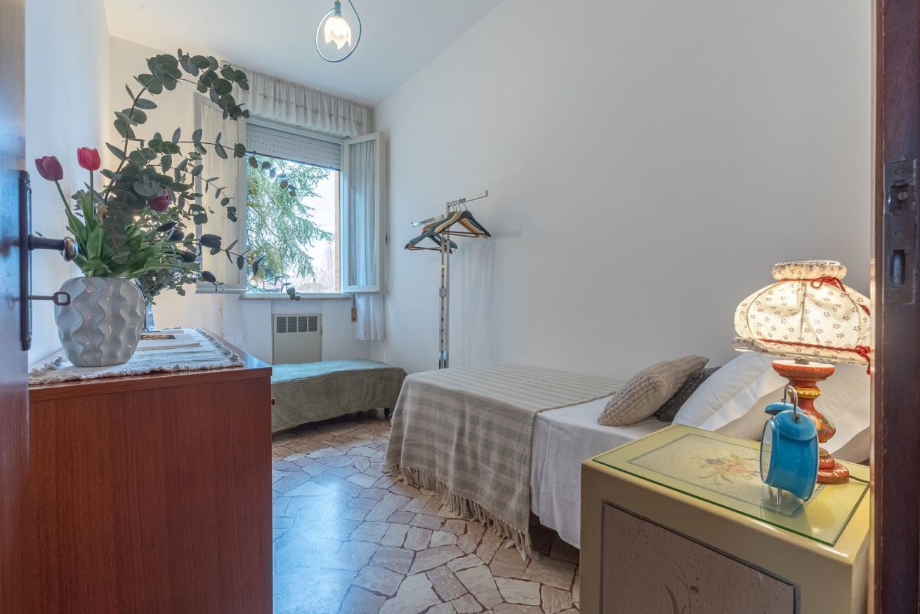 A bedroom with a bed, bedside table, lamp, and a window with curtains.