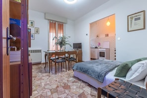 A bedroom with a bed, a desk with a chair, a television, and a kitchenette. - GuestHost - Bright and comfortable apartment, ideal for six people, located on the second floor of a modern building WITHOUT lift (stairs to access it). The apartment is equipped with two bedrooms, a living area with kitchenette, a bathroom and a private (Ferrara)