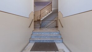 A staircase with a handrail, a landing, and a doormat at the bottom.