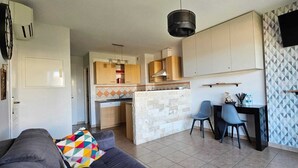 A compact living space with a kitchenette, a dining area, and a sofa.