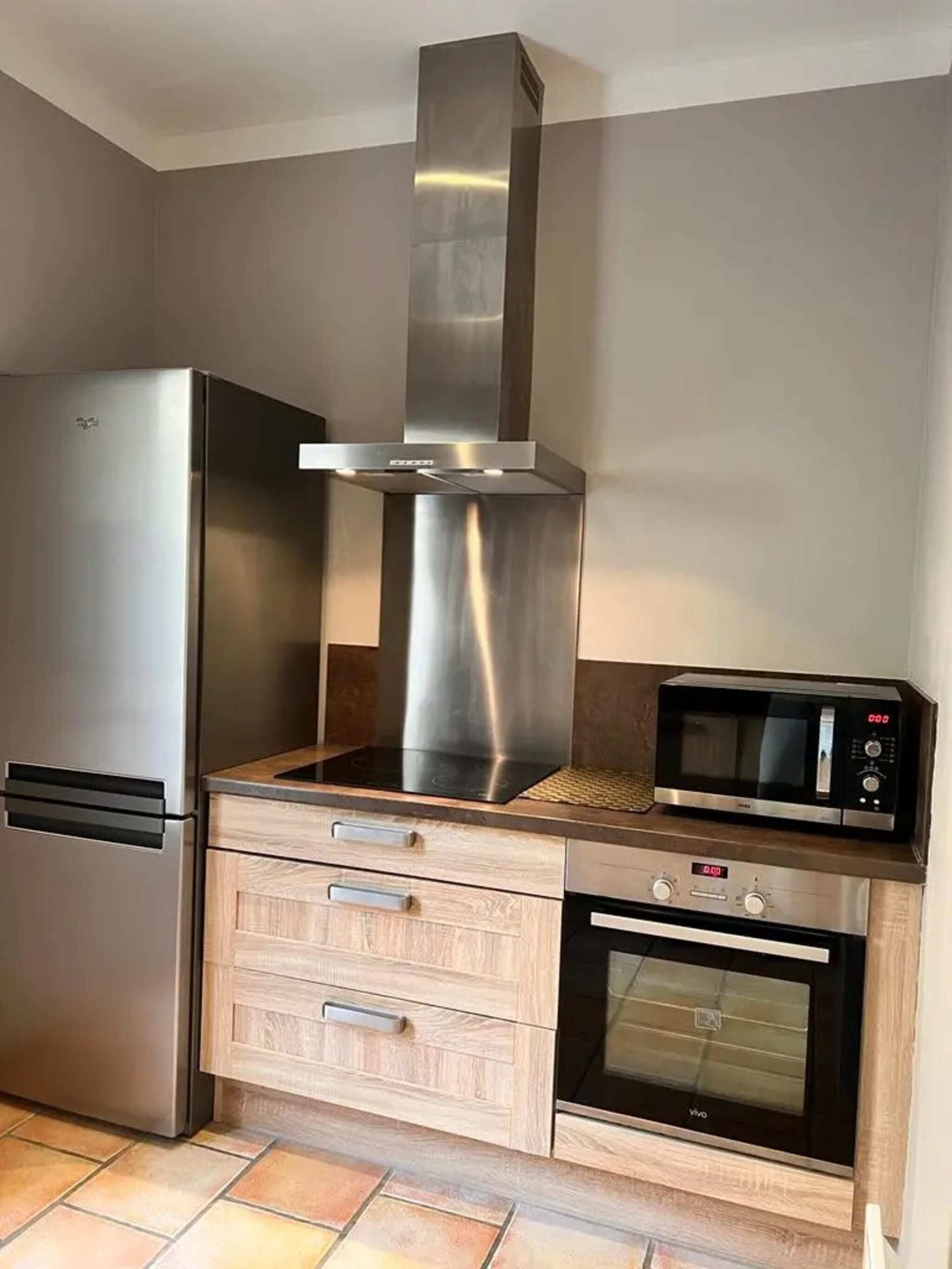 A kitchen with a stainless steel refrigerator, a microwave, and a built-in oven.