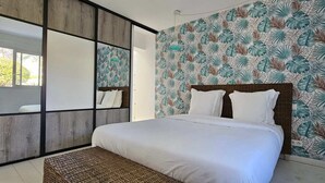 A bedroom with a large bed, a wooden-framed window, and a tropical leaf-patterned wall. - Luxury villa Les Amandiers, sea view & swimming pool (Propriano)