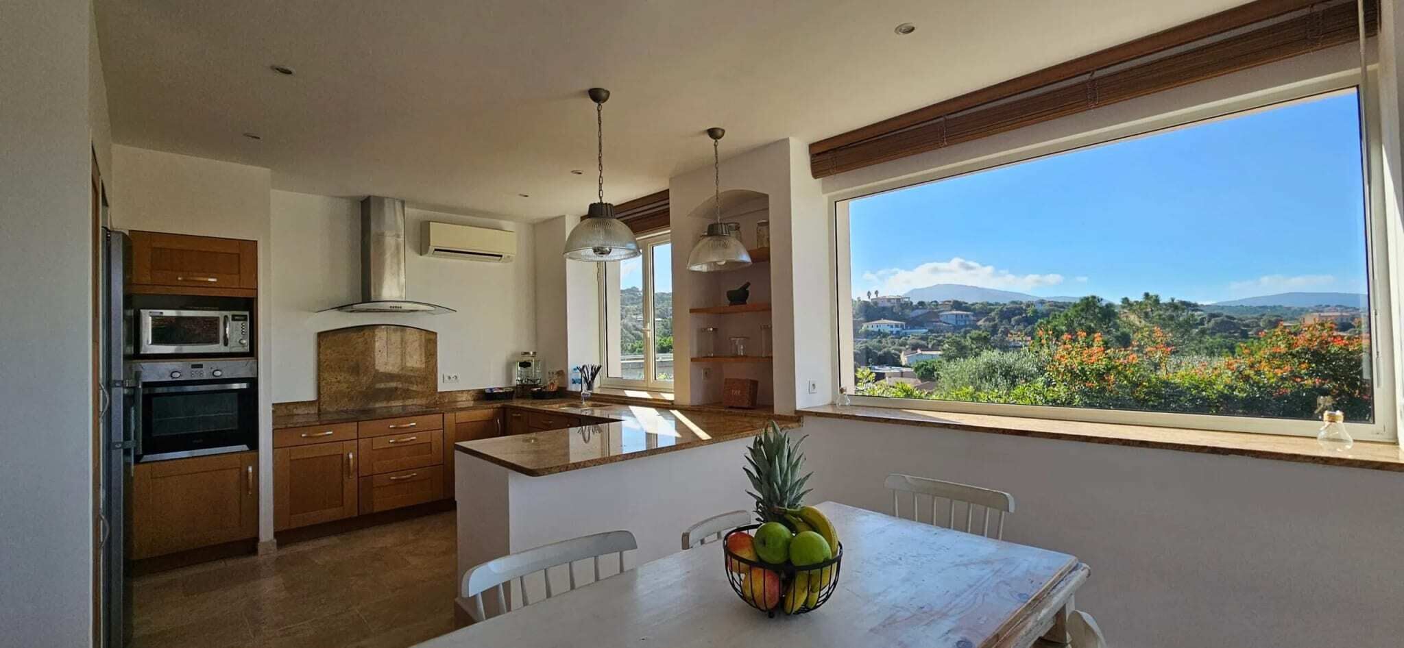 Eine moderne Küche mit Holzausstattung, einem Einbauofen und einem großen Fenster mit herrlichem Ausblick.