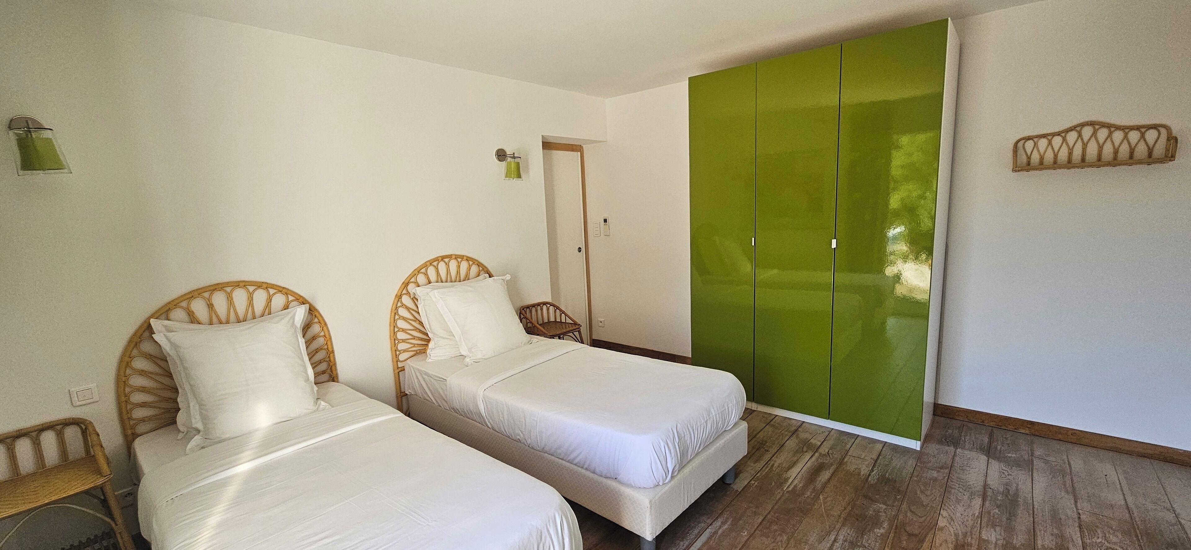 Una habitación con dos camas, un armario verde y una mesita.