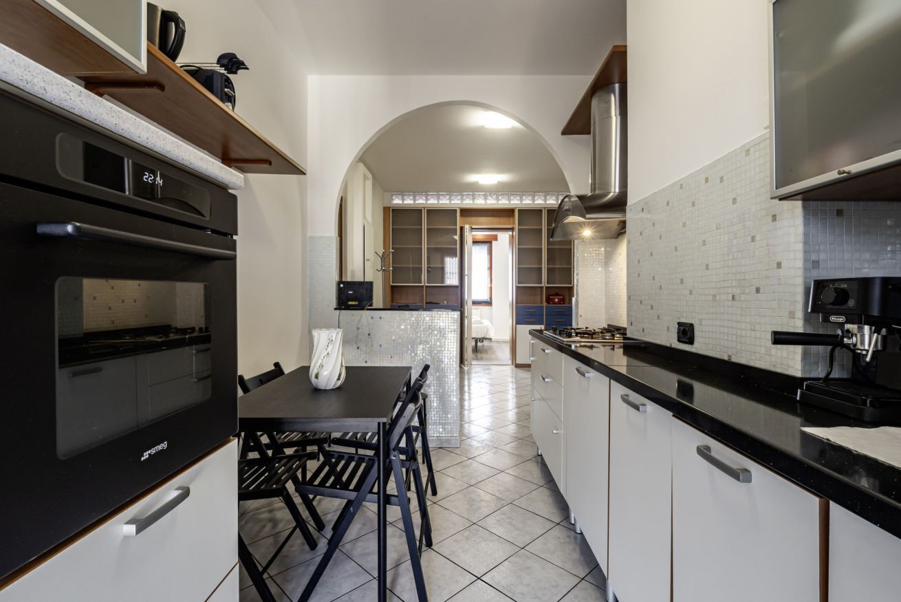 A modern kitchen with a built-in oven, a dining table with chairs, and a view into the dining area.
