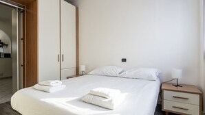 A hotel room with a bed, two bedside tables, a wardrobe, and a door leading to a bathroom.