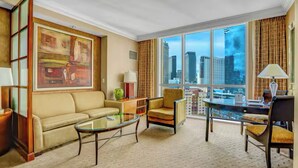 A hotel room with a large window offering a city view, a sofa, a glass coffee table, and a chair. - Sphere / F1 / Strip View/ MGM Signature Studio C21 (Las Vegas)