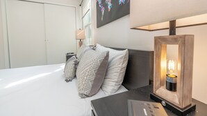 A neatly made bed with pillows, a bedside table with a lamp, and a world map on the wall.