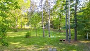 A grassy outdoor area with a table and chairs, surrounded by trees.
