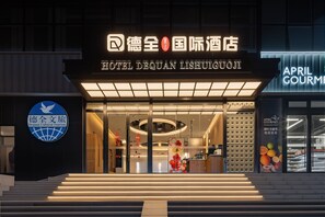 L’extérieur de l’hôtel Dequan Lishuigouji se distingue par sa façade moderne, son enseigne lumineuse et son entrée bien visible.