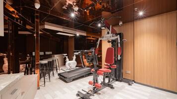 Ett gym med löpband, styrketräningsmaskiner och en spegel.