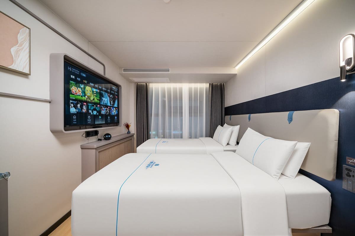 Une chambre d’hôtel moderne équipée d’un grand lit, d’un téléviseur à écran plat et d’un bureau avec un ordinateur.