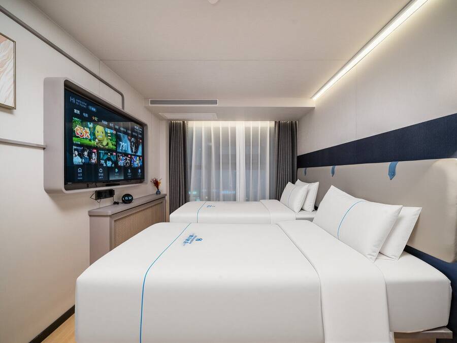 A modern hotel room with a large bed, a flat-screen TV, and a desk with a computer.