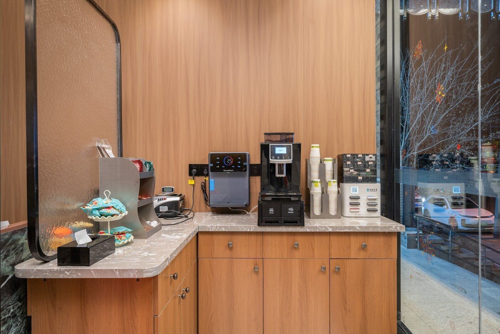 Una estación de café con una máquina de café, dispensador de agua y un refrigerador pequeño.