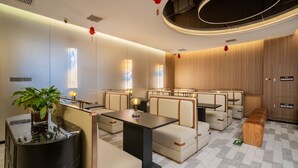 A modern hotel lobby with seating areas, a reception desk, and a large potted plant. - Beijing Yihai Culture Hotel (Beijing)