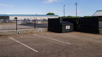 A parking lot with a fence, a building labeled "Pier 33", and a small trash bin.