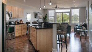 A modern kitchen with wooden cabinets, stainless steel appliances, and a central island. - Luxury Waterfront Condo (St. Joseph)