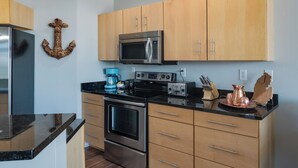 A compact kitchen with wooden cabinets, a stainless steel microwave, a coffee maker, and a toaster. - Luxury Waterfront Condo (St. Joseph)