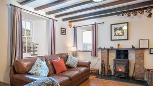 Una sala de estar acogedora con un sofá de cuero, cortinas a rayas, una chimenea y vistas al exterior.