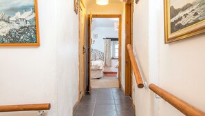 Un estrecho pasillo con barandillas de madera que conduce a un dormitorio con cama y ventana.