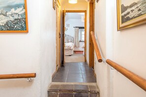 A narrow hallway with wooden handrails, leading to a bedroom with a bed and a window. - Beach Cottage, Holiday Cottage Abereiddy, Sleeps 6, 3 bedrooms,  bathrooms (Haverfordwest)